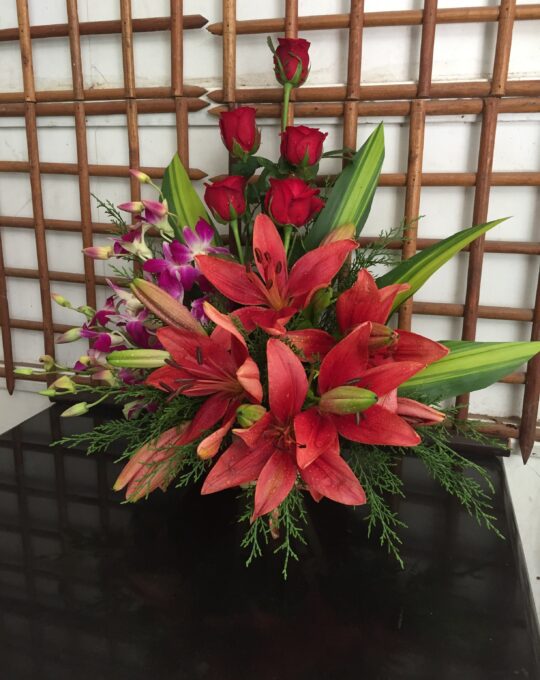 A Basket arrangement of 5 stems of lillies, 3 stems of orchids and 5 roses.